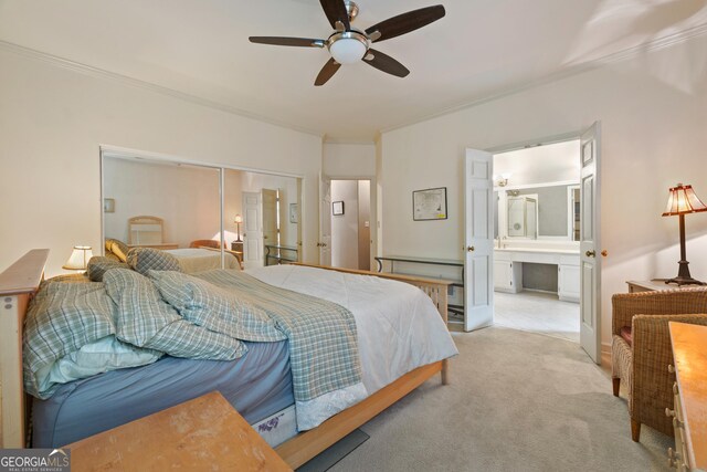carpeted bedroom with ornamental molding, a closet, ensuite bathroom, and a ceiling fan