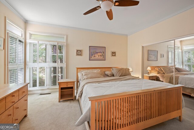 bedroom featuring light carpet, ornamental molding, and a ceiling fan