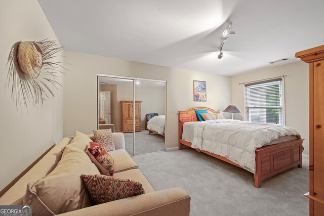 bedroom featuring light colored carpet, a closet, and track lighting