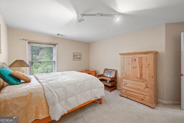 bedroom featuring rail lighting and light carpet