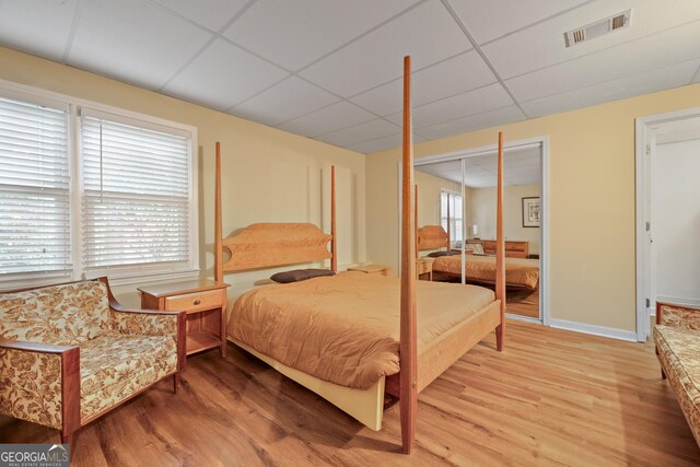 bedroom featuring a paneled ceiling, light wood-style floors, and baseboards