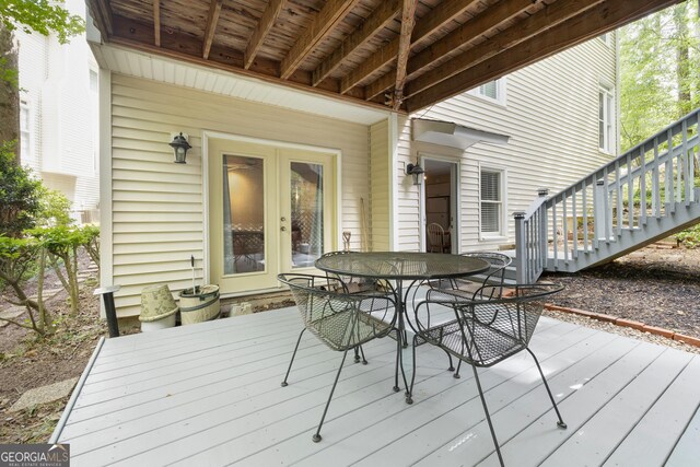 deck with french doors, outdoor dining space, and stairway
