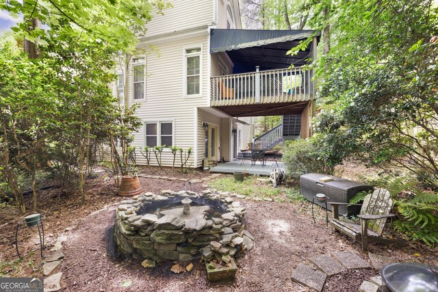 back of property featuring a fire pit, a wooden deck, and stairs