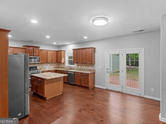 kitchen featuring appliances with stainless steel finishes, a sink, tasteful backsplash, dark wood finished floors, and recessed lighting