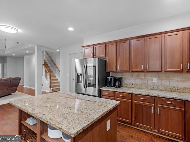 kitchen featuring stainless steel fridge with ice dispenser, open shelves, dark wood-style floors, tasteful backsplash, and light stone counters