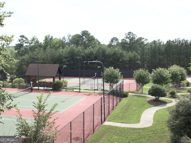 view of tennis court featuring fence and a lawn