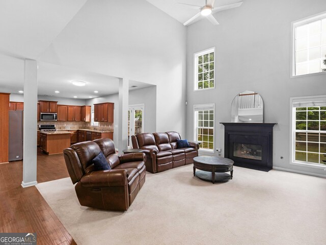 living area featuring high vaulted ceiling, a ceiling fan, a glass covered fireplace, dark wood finished floors, and recessed lighting