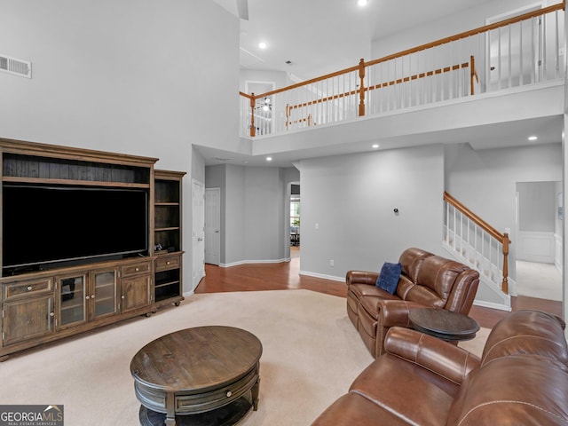 living room featuring a towering ceiling, stairs, baseboards, wood finished floors, and recessed lighting