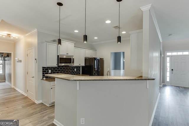 9565 Rushmore Cir, Braselton, GA 30517 - kitchen featuring stainless steel microwave, black fridge, ornamental molding, baseboards, and light wood-style floors