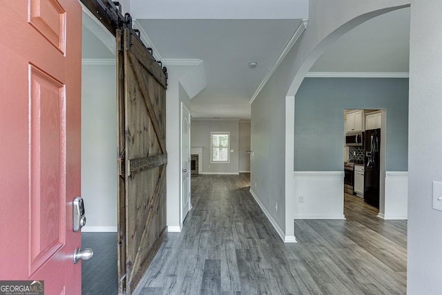 9565 Rushmore Cir, Braselton, GA 30517 - entryway featuring a barn door, crown molding, wood finished floors, arched walkways, and baseboards