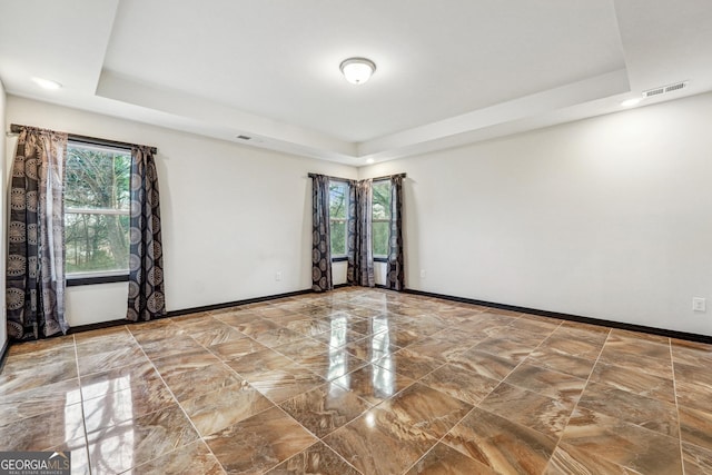 spare room featuring a tray ceiling, healthy amount of natural light, baseboards, and recessed lighting