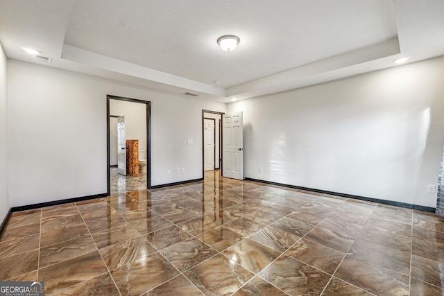 empty room with a raised ceiling, baseboards, marble tiled flooring, and recessed lighting