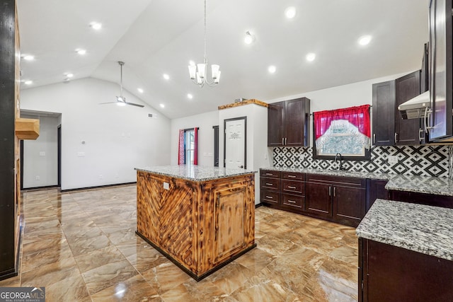 kitchen with light marble finish floors, a kitchen island, a sink, tasteful backsplash, and light stone countertops