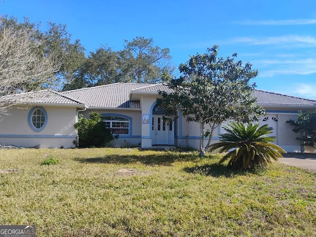 ranch-style house featuring a tile roof, a front yard, stucco siding, and an attached garage