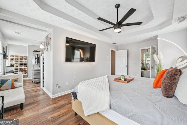 2349 June Springs Dr SW, Marietta, GA 30008 - bedroom with a raised ceiling, wood finished floors, a walk in closet, baseboards, and ceiling fan
