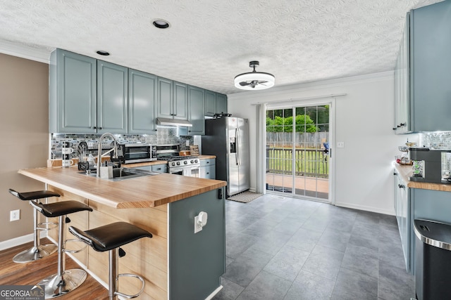 2349 June Springs Dr SW, Marietta, GA 30008 - kitchen featuring stainless steel appliances, wooden counters, ornamental molding, under cabinet range hood, and decorative backsplash
