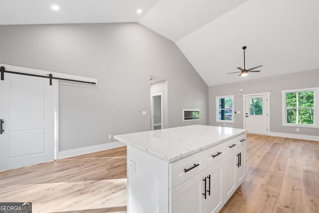 103 Spruce Ln, Eatonton, GA 31024 - kitchen with a barn door, ceiling fan, a kitchen island, light wood-style flooring, and light stone counters