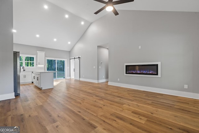 103 Spruce Ln, Eatonton, GA 31024 - unfurnished living room featuring high vaulted ceiling, light wood-style flooring, a glass covered fireplace, ceiling fan, and recessed lighting