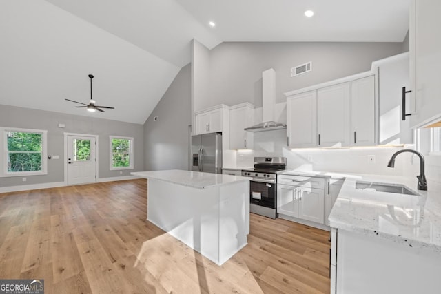 103 Spruce Ln, Eatonton, GA 31024 - kitchen featuring stainless steel appliances, wall chimney range hood, high vaulted ceiling, a center island, and white cabinets