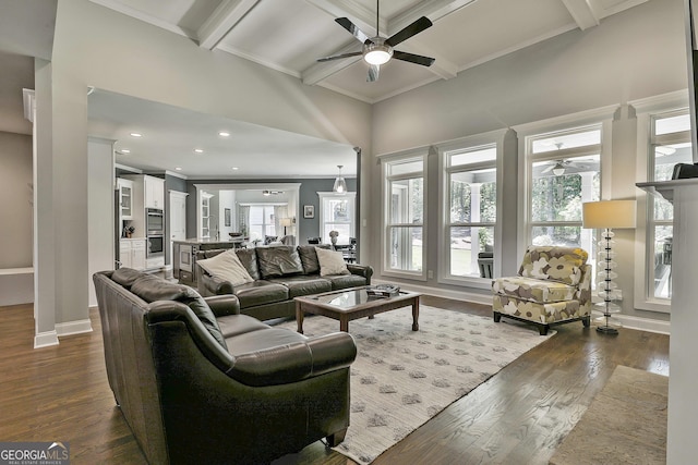 living room with ceiling fan, ornamental molding, dark wood finished floors, beamed ceiling, and baseboards