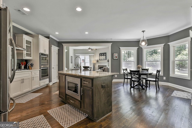 kitchen featuring stainless steel appliances, a sink, crown molding, healthy amount of natural light, and dark brown cabinets