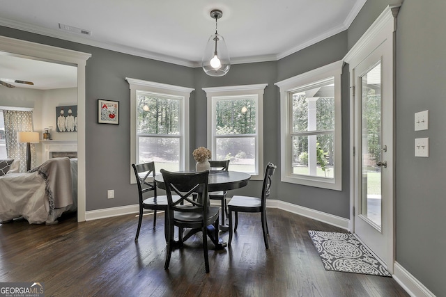 dining space featuring dark wood finished floors, healthy amount of natural light, baseboards, and crown molding