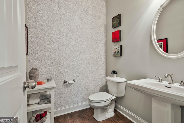 bathroom featuring baseboards, wood finished floors, and toilet