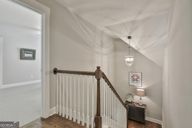 stairway featuring wood finished floors, baseboards, and a chandelier