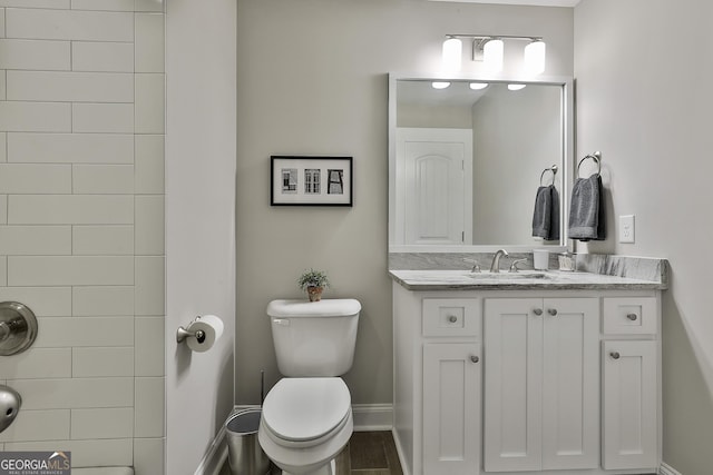 full bath featuring toilet, vanity, and baseboards