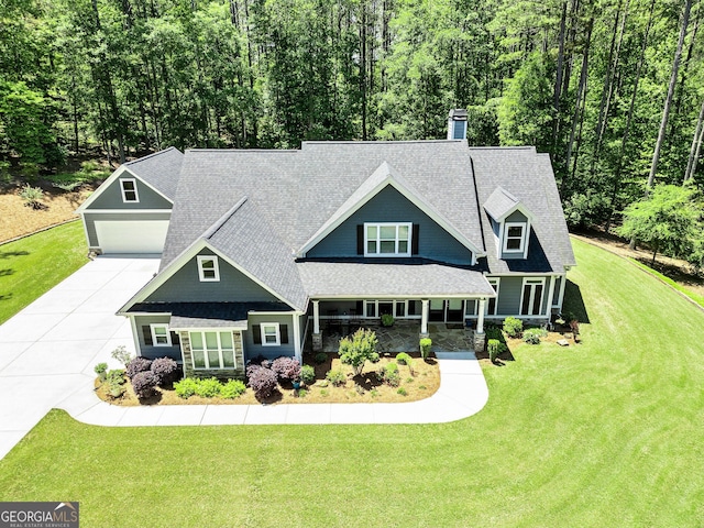 view of front of house featuring driveway, a garage, a shingled roof, a front yard, and a chimney