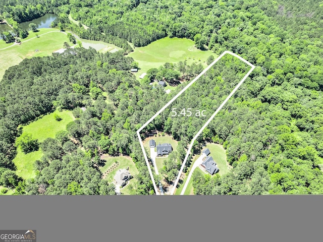 aerial view of property and surrounding area featuring property boundaries highlighted, a heavily wooded area, and a large body of water