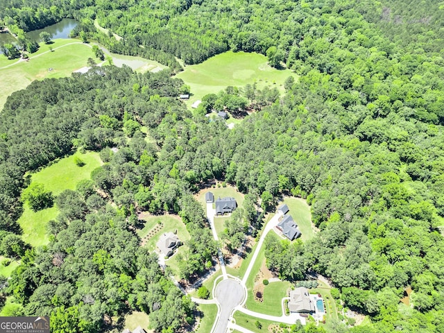 aerial view of property and surrounding area featuring a forest, a large body of water, and a local golf course