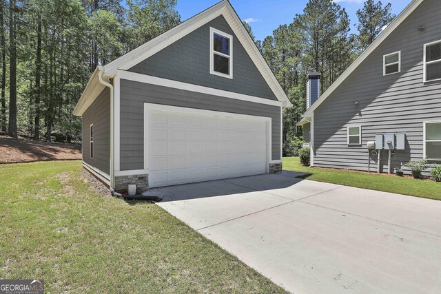 view of side of property with a garage, a lawn, and stone siding