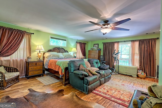 bedroom featuring multiple windows, wood finished floors, and ceiling fan