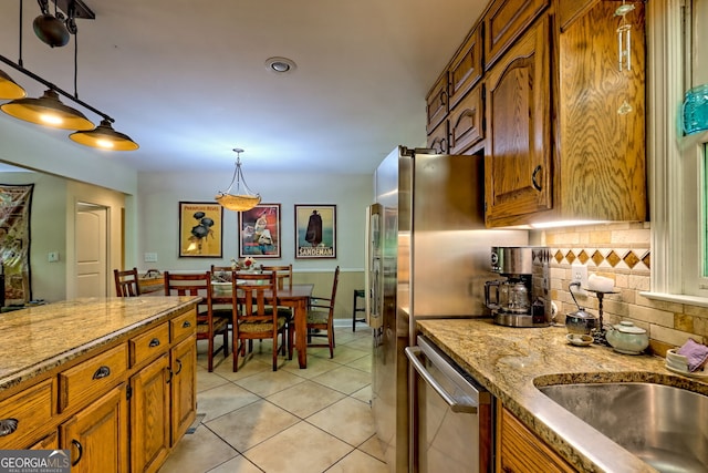 kitchen featuring dishwasher, brown cabinets, backsplash, and light tile patterned flooring