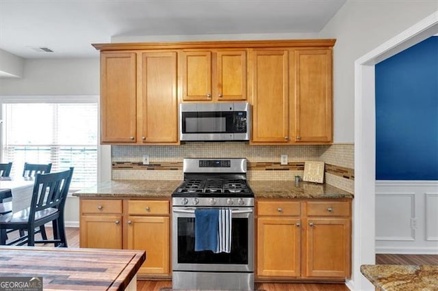 10 Bayberry Ct, Acworth, GA 30101 - kitchen featuring appliances with stainless steel finishes, stone counters, light wood finished floors, decorative backsplash, and a wainscoted wall