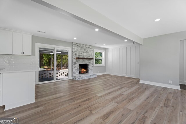 2604 Flat Shoals Rd SW, Conyers, GA 30094 - unfurnished living room with light wood-type flooring, a stone fireplace, recessed lighting, and baseboards
