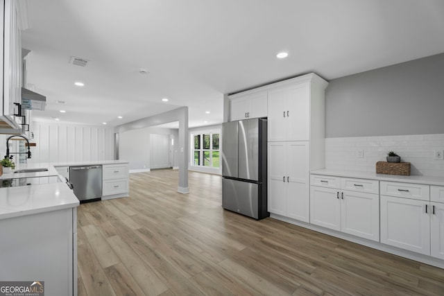 2604 Flat Shoals Rd SW, Conyers, GA 30094 - kitchen with stainless steel appliances, a sink, light wood-type flooring, white cabinetry, and tasteful backsplash