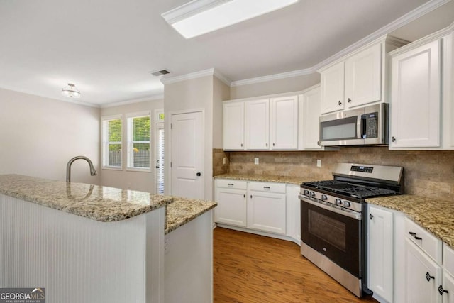 kitchen featuring stainless steel appliances, white cabinetry, tasteful backsplash, ornamental molding, and light wood-type flooring