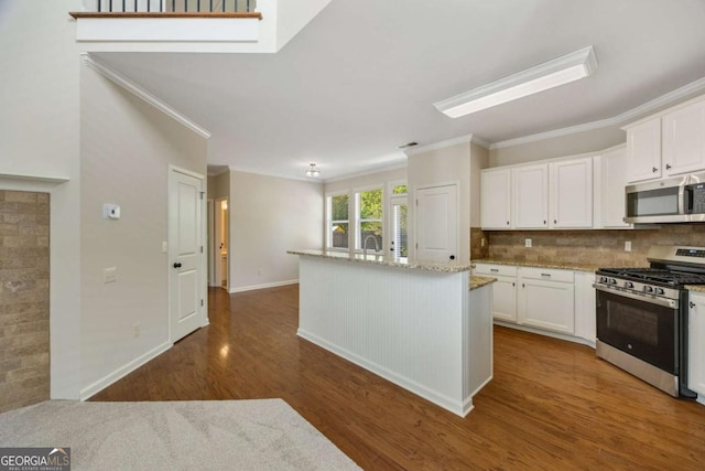 kitchen with appliances with stainless steel finishes, crown molding, dark wood finished floors, white cabinets, and light stone counters