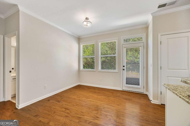 unfurnished dining area featuring wood finished floors, healthy amount of natural light, ornamental molding, and baseboards