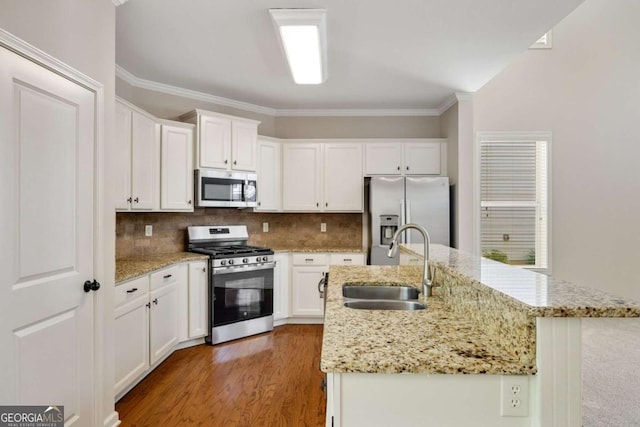 kitchen featuring appliances with stainless steel finishes, a sink, white cabinetry, a kitchen island with sink, and crown molding