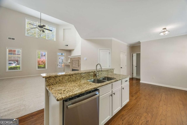 kitchen featuring stainless steel dishwasher, a sink, ceiling fan, open floor plan, and baseboards