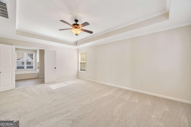 unfurnished bedroom with a raised ceiling, carpet flooring, ornamental molding, baseboards, and a ceiling fan