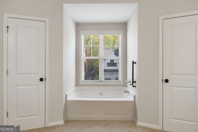 bathroom with baseboards, a garden tub, and tile patterned floors