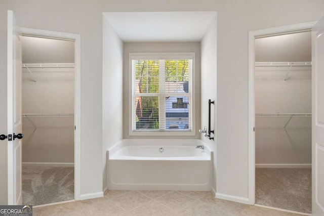 bathroom with a garden tub and baseboards