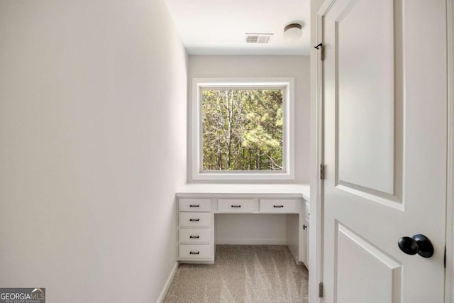 interior space featuring built in study area and light carpet