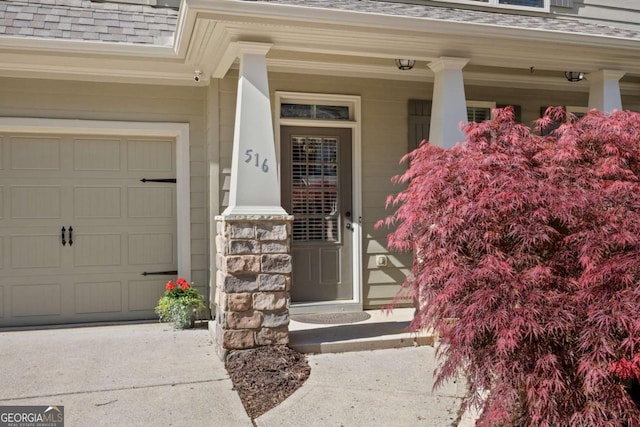 property entrance featuring a shingled roof, covered porch, and driveway