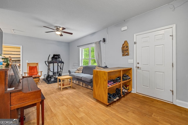 living area featuring light wood finished floors, a ceiling fan, and a textured ceiling