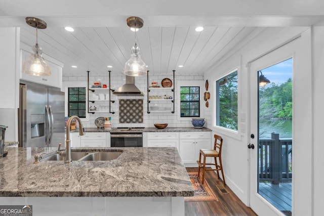 kitchen featuring a sink, stainless steel appliances, wall chimney range hood, dark wood-style flooring, and white cabinetry